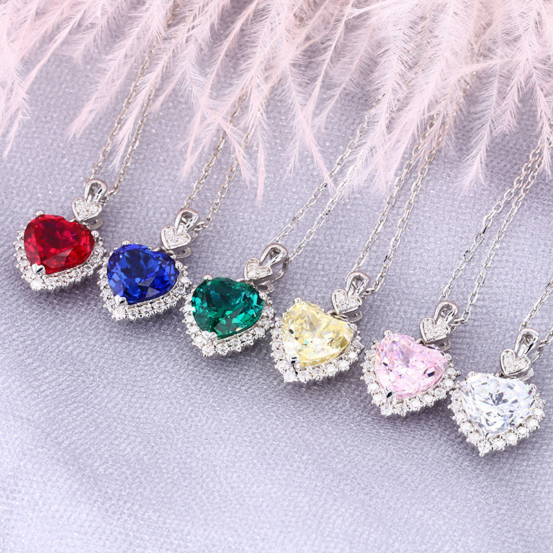 Set of heart-shaped gemstone necklaces on a light pink feathered background