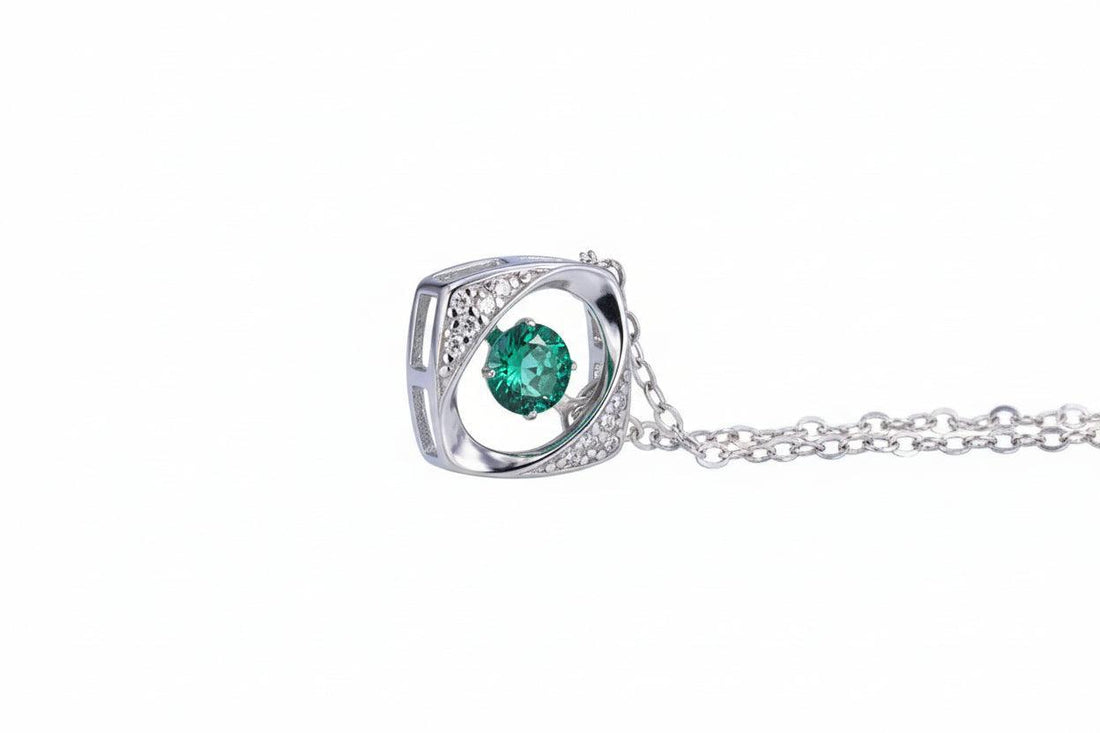 Silver necklace with a green gemstone pendant on a white background