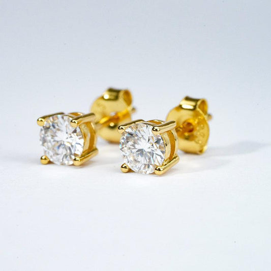 Gold stud earrings with clear gemstones on a light gray background